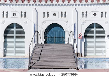 Foreground Of Wooden Bridge And Pond In The Back Facade Of The Moruno Building In The City Of Castel