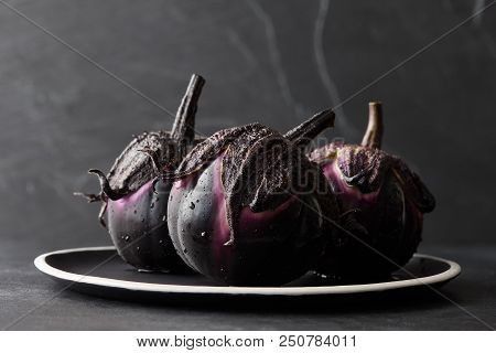 Fresh Italian Type Eggplants Or Aubergines With Water Drops In Black Plate On Dark Stone Background