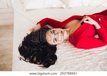 Above View Of Goergous And Fashionable Woman In Red Low Neckline Dress Lying And Resting On White Be