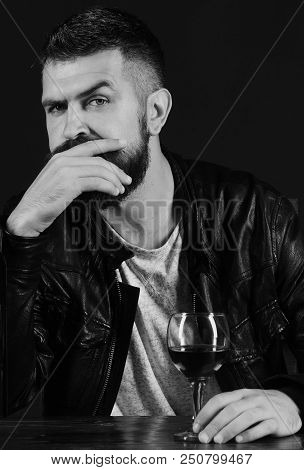 Man With Beard Holds Glass Of Wine On Dark Brown Background. Winetasting And Degustation Concept. So