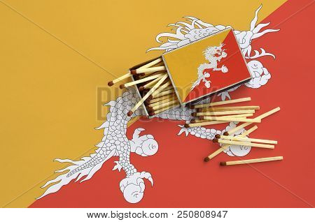Bhutan Flag  Is Shown On An Open Matchbox, From Which Several Matches Fall And Lies On A Large Flag.
