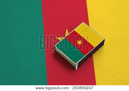 Cameroon Flag  Is Pictured On A Matchbox That Lies On A Large Flag.