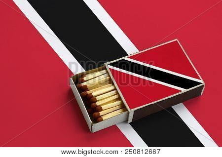 Trinidad And Tobago Flag  Is Shown In An Open Matchbox, Which Is Filled With Matches And Lies On A L