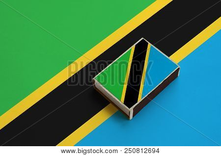 Tanzania Flag  Is Pictured On A Matchbox That Lies On A Large Flag.