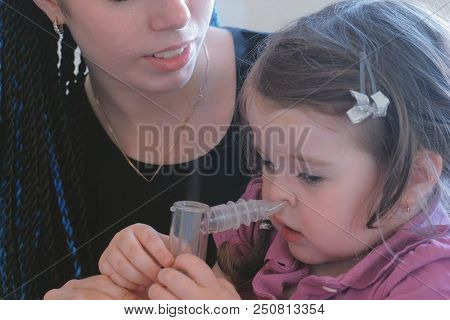 Little Cute Girl Inhaling Through Inhaler Mask With Her Mom. Use Nebulizer And Inhaler For The Treat