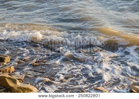 Pebbles On The Beach Pebbles On The Sea Shore And Waves Of Water Illuminated By The Rays Of The Sun