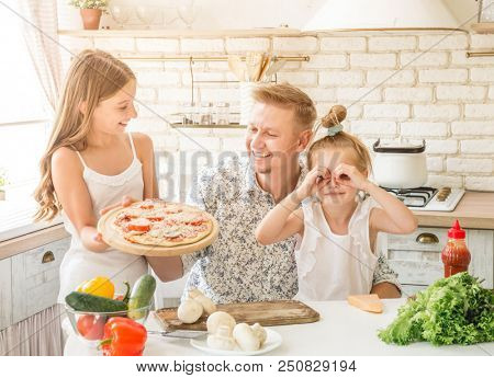 dad with two little daughters preparing pizza in the kitchen
