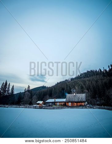 Rural wooden cottage in the mountains in evening. Wooden hut on hill moutains with old fence