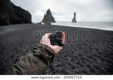 Black rocks on hand from black sand beach Reynisfjara Vik ,Iceland.