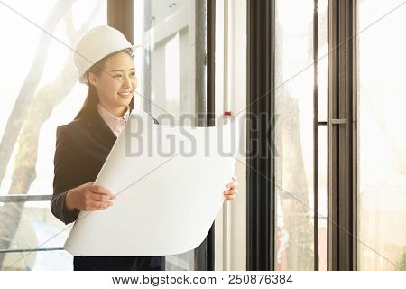 Asian Woman Engineers Waer Safety Helmet Standing Working With Blueprint At Site Office