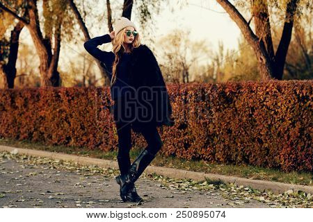 Autumn fashion shot. Trendy young woman in warm clothes posing in the autumn park. Youth style.
