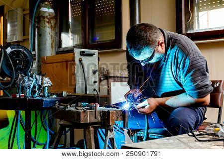Sculptor Is Using Arc Welding To Assembly Metal Sculpture Barehanded With Protective Spectacles.
