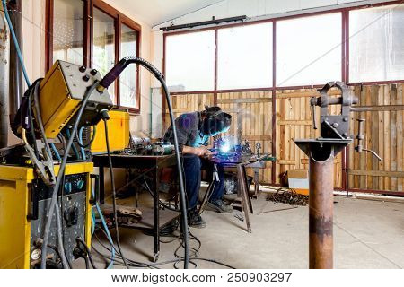 Sculptor Is Using Arc Welding To Assembly Metal Sculpture Barehanded With Protective Mask.