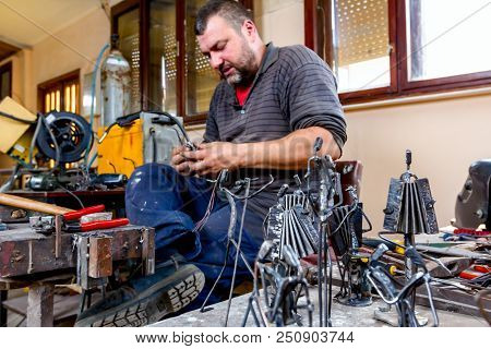 Sculptor Is Making Creative Figures Of Musicians Of Metal Wire In His Workshop. Accordionists Are Pl