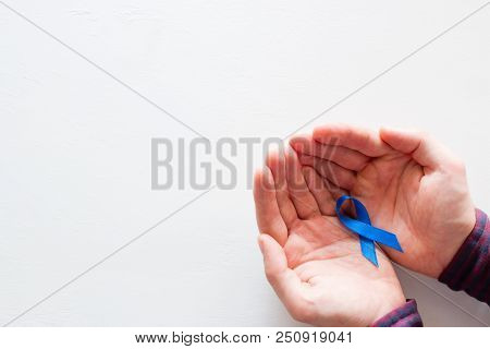 Man Holds A Blue Ribbon On A White Background With Space For Text