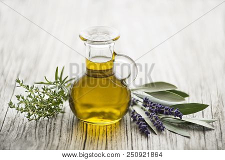 Olive Oil With Fresh Herbs On Wooden Background