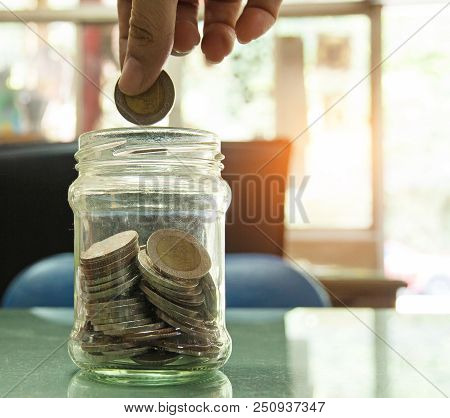 Closeup The Glass Bottle And Coin,humand Hand Is Filling Coin For Investment In Future,save Money Fo