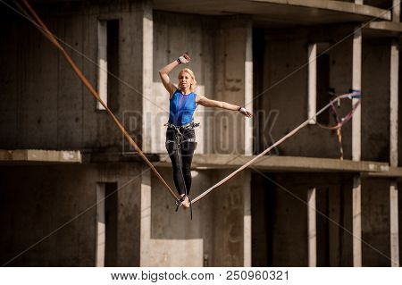 Female Equilibrist Standing With One Arm Raised And Other To The Right On The Slackline Rope On The 