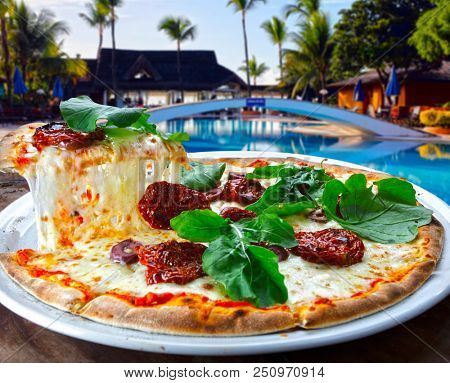 Pizza with dried tomatoes, rucula and mozzarella in pizzeria