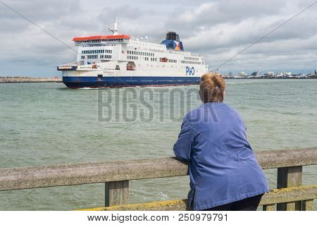 Calais, France - 19 June 2018: Woman Watching A Cross Channel Ferry Leaving The Port Of Calais
