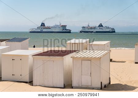 Calais, France - 19 June 2018: Beach Cabins And Dfds / P&o Cross Channel Ferries.