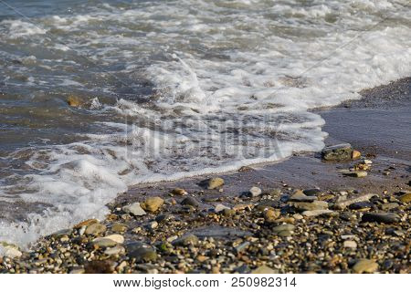 Pebbles On The Beach Pebbles On The Sea Shore And Waves Of Water Illuminated By The Rays Of The Sun
