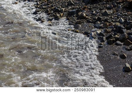 Pebbles On The Beach Pebbles On The Sea Shore And Waves Of Water Illuminated By The Rays Of The Sun