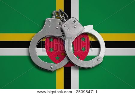 Dominica Flag  And Police Handcuffs. The Concept Of Observance Of The Law In The Country And Protect