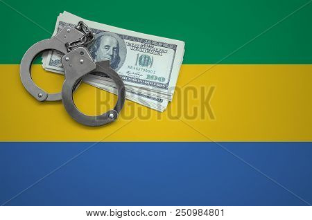 Gabon Flag  With Handcuffs And A Bundle Of Dollars. The Concept Of Breaking The Law And Thieves Crim