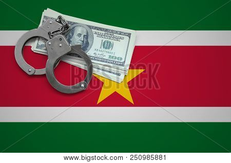 Suriname Flag  With Handcuffs And A Bundle Of Dollars. The Concept Of Breaking The Law And Thieves C