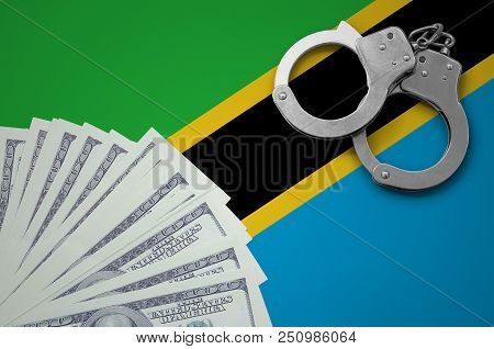 Tanzania Flag  With Handcuffs And A Bundle Of Dollars. The Concept Of Illegal Banking Operations In 