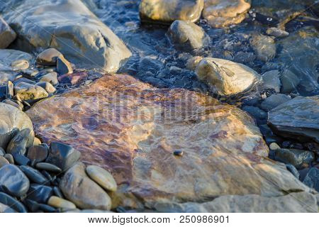 Pebbles On The Beach Pebbles On The Sea Shore And Waves Of Water Illuminated By The Rays Of The Sun