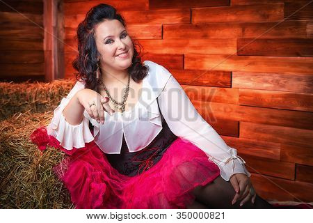Portrait Of Fat Plump Fun Charming Cute Woman With Black Curly Hair In The Room With Hay And Straw