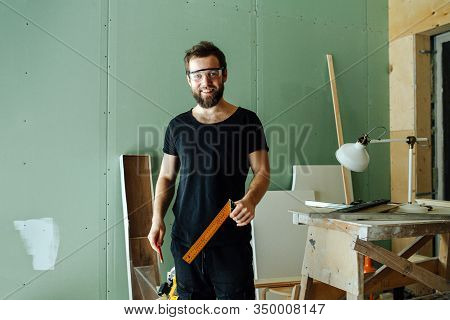 Handsome Smiling Bearded Man Standing With Corner Ruler In Rennovating Apartment
