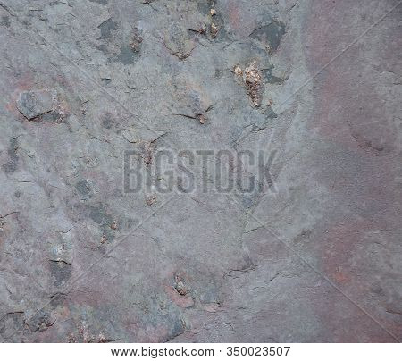 The Texture Of Natural Stone With Traces Of Erosion And Delamination On A Gray Surface.