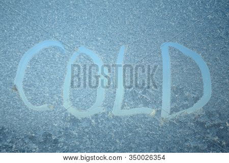 The Inscription On Frozen Window Pane. Wor Cold Written On Blurry Translucent Background. Stock Phot
