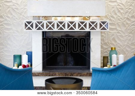 An organized resting place for the owner of the house and his wife by the fireplace. A cozy corner with two blue armchairs and a set of candles to give the atmosphere a special romanticism.