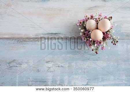 Easter Vintage Background. Natural Colored Easter Eggs In A Nest Of Flowers On Gray Shabby Wooden Pl