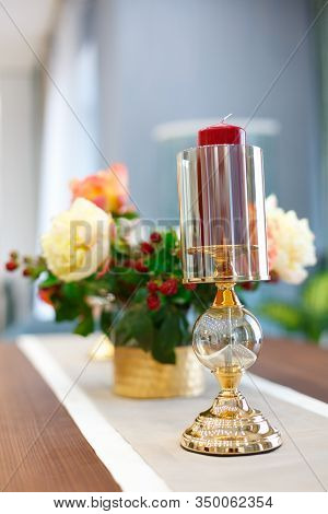 Glass hanging on the tablecloth. Against the background of a bouquet of beautiful red flowers.