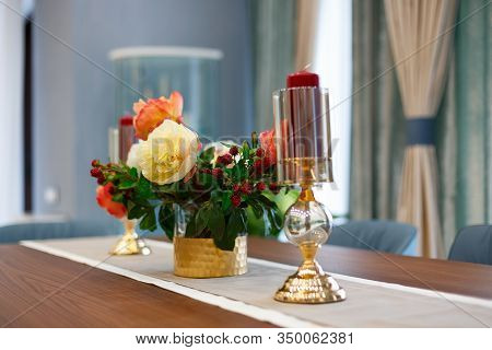 Glass hanging on the tablecloth. Against the background of a bouquet of beautiful red flowers.