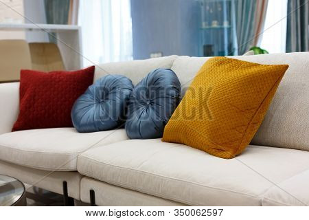 Red, blue and brown pillows on a white sofa, living room interior