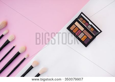 Side View Of Colorful Metallized Eyeshadow Pallete And Natural Makeup Brushes Set On White And Pink 
