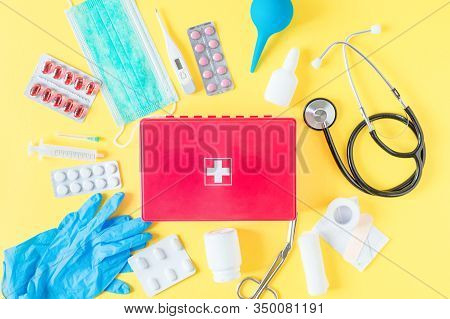 First Aid Kit Red Box With Medical Equipment And Medications For Emergency Top View On Pastel Yellow
