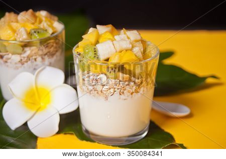 Exotic Tropical Fruit Salad With Muesli And Yogurt In A Glasses On The Palm Leaf.