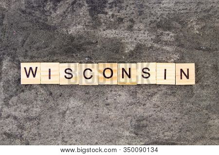 Wisconsin Word Written On Wood Block, On Gray Concrete Background. Top View.