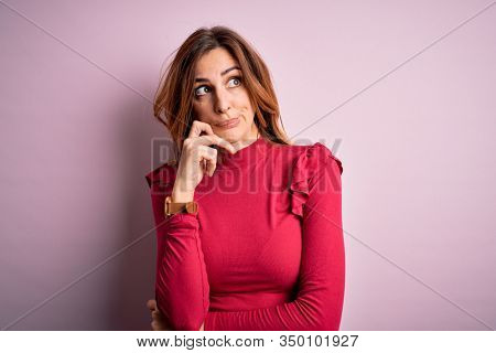 Young beautiful brunette woman wearing casual sweater stnding over pink background with hand on chin thinking about question, pensive expression. Smiling with thoughtful face. Doubt concept.