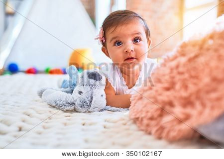 Beautiful infant happy at kindergarten around colorful toys lying on blacket