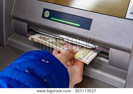 A Woman At An Atm Withdraws Cash Hryvnias In Ukraine, 100 And 500 Hryvnia Notes