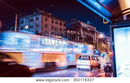 Night scene of tram in traffic at crossing with lighttrail motion blur