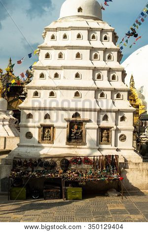 White Religious Building With Bas-reliefs Of Hindu Gods In Swayambhunath Temple In Kathmandu. Nearby